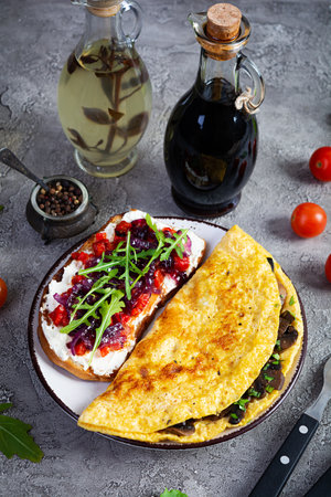 Fried omelet stuffed with mushrooms and sandwich with grilled peppers and caramelized onions