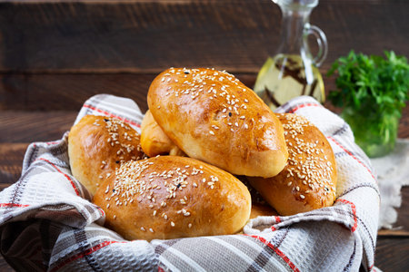 Delicious cabbage pies on wooden background. Baked homemade pirozhki with cabbageの写真素材