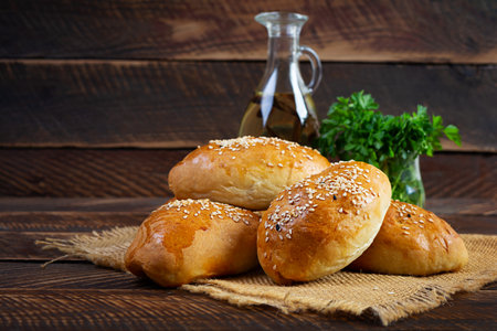 Delicious cabbage pies on wooden background. Baked homemade pirozhki with cabbageの写真素材