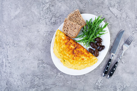 Fried omelette with onion, herbs and olives. Delicious breakfast with eggs and toasts