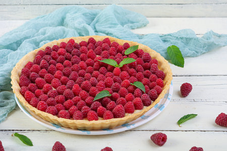 Delicious tart with custard and raspberries. Raspberry cake decorated with mint leaves