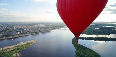 Hot air balloon is flying over a city and a river. The balloon is red and is the size of a heart. Nizhny Novgorodの写真素材