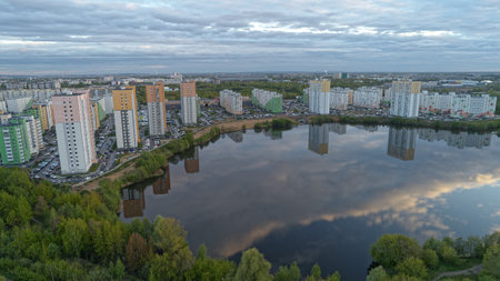 City with a lake in the middle. The lake is reflecting the buildings and the sky. The sky is cloudy and the sun is setting. Nizhny Novgorodの写真素材