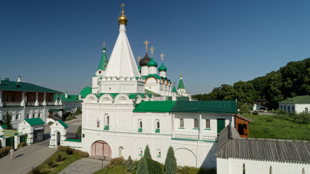 Large white building with a green roof and a green dome. The building is surrounded by trees and has...