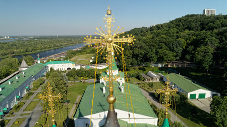 Large building with a gold cross on top. The building is surrounded by trees and he is a church. The...