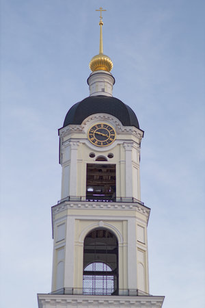Tall clock tower with a gold cross on top. The clock is set at 10:30. The monastery of the Sarov...