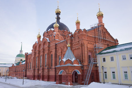 Large red brick building with a dome and gold trim. The building is surrounded by snow and has a...