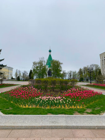 Large green building with a statue of a man in front of it. The statue is surrounded by a flower gardenの写真素材