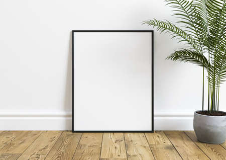 Black horizontal frame mockup on wooden floor with green plant in a vase and white wall behind it....