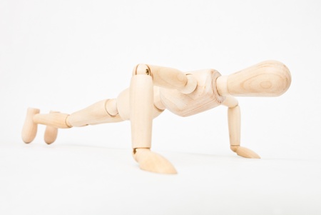 Wooden mannequin doing push-ups on white backgroundの写真素材