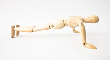 Wooden mannequin doing push-ups on white backgroundの写真素材