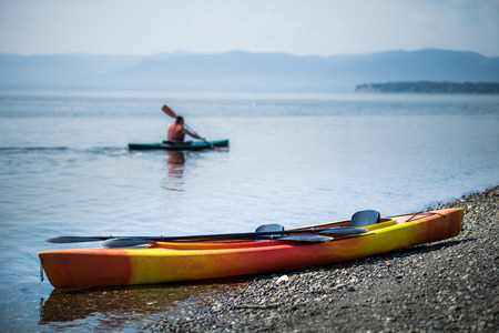 Orange and Yellow Kayak on the Sea Shore During a beautiful Day of Summer with Unrecognizable People...