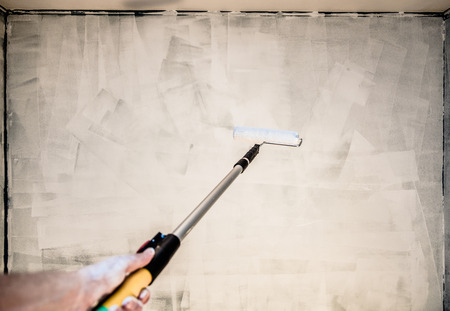 POV of Someone Painting the Wall with Roller Pinの写真素材