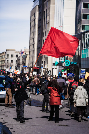 MONTREAL, CANADA, APRIL 02 2015. Riot in the Montreal Streets to counter the Economic Austerity Measures. Protester Agitating a Red Flag in the Streetのeditorial素材