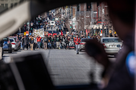 MONTREAL, CANADA, APRIL 02 2015. Riot in the Montreal Streets to counter the Economic Austerity Measures. View of the First line of Protesters walking in the Street Through a Police Car Windowのeditorial素材