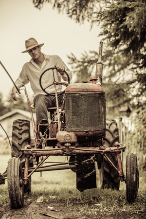 Young Farmer Driving a Red Old Vintage Tractorの写真素材