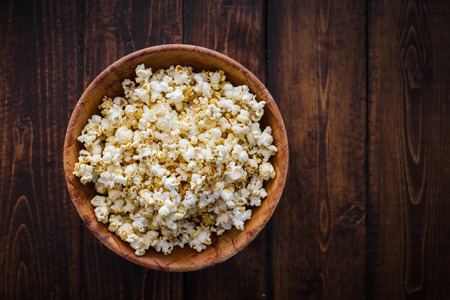 Spiced Popcorn in a Wooden Bowl on a Table in the Living Roomの写真素材