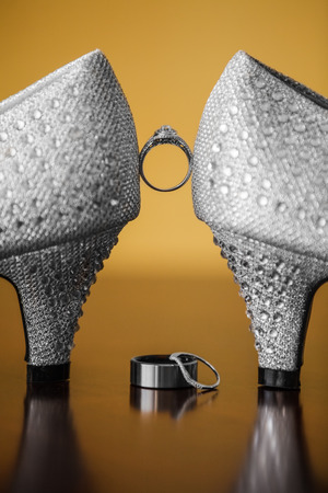 Pair of Wedding Shoes and Bands Closeup on a Tableの写真素材