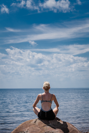 Young Woman doing Lotus Yoga Position in Front of the Oceanの写真素材