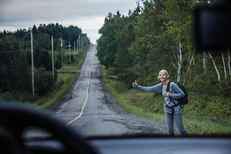View from Inside a Car of a Blonde Woman Hitchhiking on the Side of the Roadの写真素材