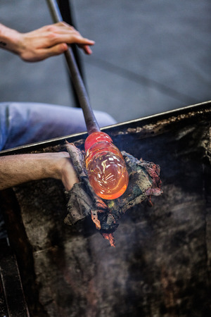 Man Hands Closeup Shaping a Blown Glass Piece with a Wet Newspaperの写真素材