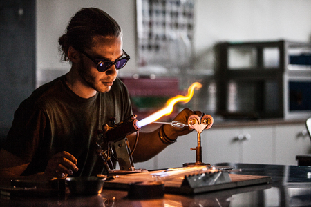 Glassblowing Professional Working on a Torch Flame with Glass Tubesの写真素材