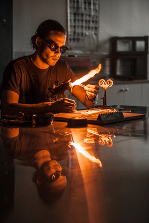 Glassblowing Professional Working on a Torch Flame with Glass Tubesの写真素材