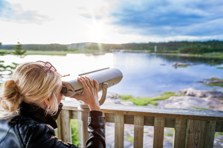 Young Woman Looking at the Amazing Nature Through a Binocular in a Observation Tower in Quebec, Canada.の写真素材