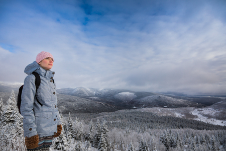 Young Satisfied Woman Looking at the View from the Top of a Mountain in Winterの写真素材