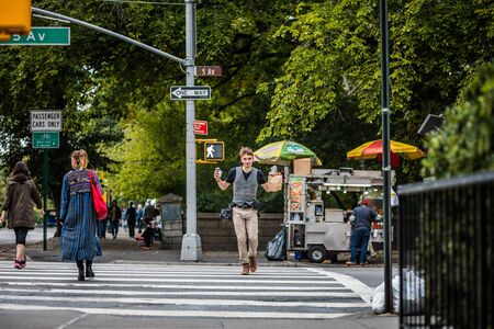 NEW YORK, USA - October 13, 2016. Happy Tourist Photographer just got a Snack from the Fast Food Cart near Central Park, NYC.のeditorial素材