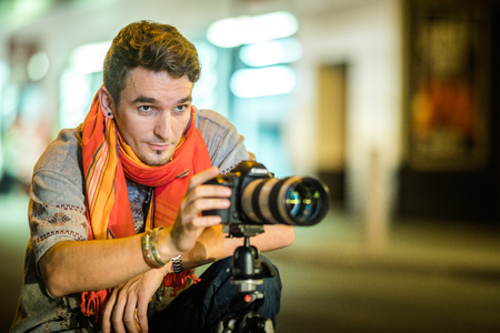 NEW YORK, USA - October 14, 2016. Photographer in the Street of New York taking a long Exposure Picture of Time Square at Night with a Long Zoom Lensのeditorial素材