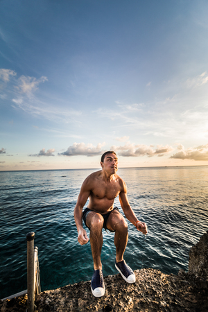 SAN ANDRES ISLAND, Colombia _ Circa March 2017. Person Jumping down a little Volcanic Rock Cliff into the Caribbean Sea of San Andres during a Beautiful Sunset.のeditorial素材