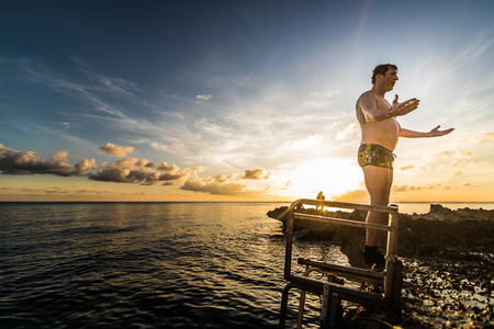 SAN ANDRES ISLAND, Colombia _ Circa March 2017. Person Jumping down a little Volcanic Rock Cliff into the Caribbean Sea of San Andres during a Beautiful Sunset.のeditorial素材
