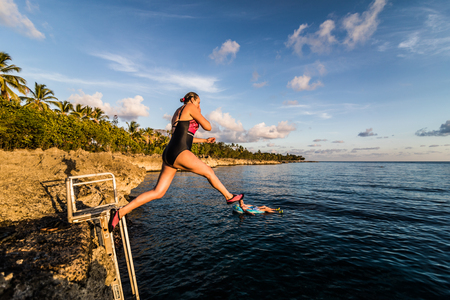 SAN ANDRES ISLAND, Colombia _ Circa March 2017. Person Jumping down a little Volcanic Rock Cliff into the Caribbean Sea of San Andres during a Beautiful Sunset.のeditorial素材