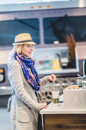 MONTREAL, CANADA _March 16th 2017. Young Woman at the Starbucks of Montreal Airport Stirring her Coffeeのeditorial素材