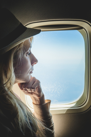 Young Caucasian Tourist Woman Alone Looking Outside and Sitting inside Airplane  While Going in Vacationの写真素材
