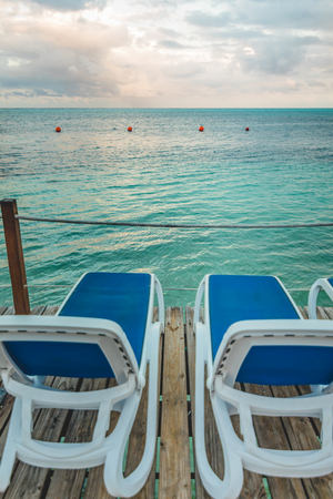 Wooden Pier and Long Blue Chairs with Nobody and Copy Space for Textの写真素材