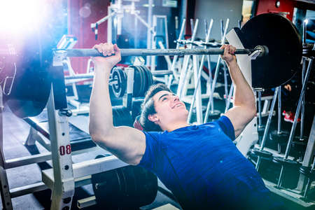 Muscular athletic man pressing barbell on incline bench looking confident.の写真素材