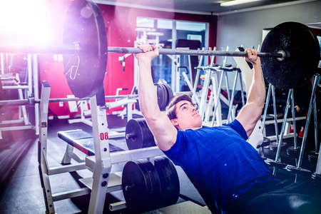 Muscular athletic man pressing barbell on incline bench looking confident.の写真素材