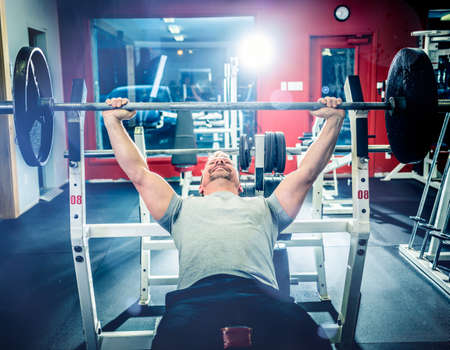 Muscular athletic man pressing barbell on incline bench looking confident.の写真素材
