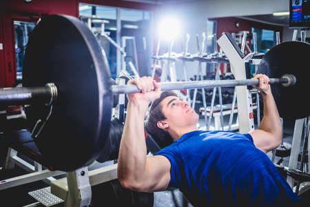 Muscular athletic man pressing barbell on incline bench looking confident.の写真素材