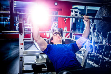 Muscular athletic man pressing barbell on incline bench looking confident.の写真素材