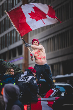 Ottawa, Ontario, Canada - January 30 2022. Happy Shirtless Man Waving Canadian Flag in the Cold for the Convoy for Freedom 2022 Trucks and Tracors Protestのeditorial素材
