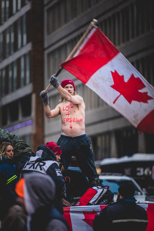 Ottawa, Ontario, Canada - January 30 2022. Happy Shirtless Man Waving Canadian Flag in the Cold for the Convoy for Freedom 2022 Trucks and Tracors Protestのeditorial素材