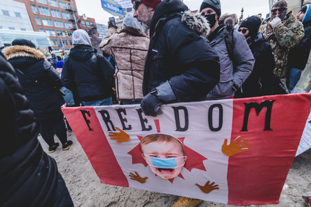 Ottawa, Ontario, Canada - January 30 2022. Big Canadian Flag with Masked Baby Crying during th Convoy for Freedom 2022 Trucks and Tracors Protestのeditorial素材