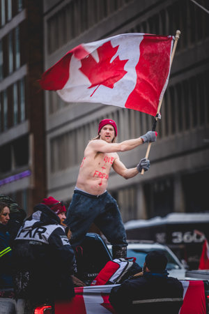 Ottawa, Ontario, Canada - January 30 2022. Happy Shirtless Man Waving Canadian Flag in the Cold for the Convoy for Freedom 2022 Trucks and Tracors Protestのeditorial素材