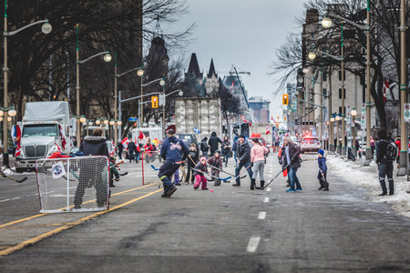 Ottawa, Ontario, Canada - February 11, 2022. People and kids playing hockey in front of parliament during Freedom Convoy Protest in Ottawa.のeditorial素材