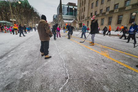Ottawa, Ontario, Canada - February 12, 2022. People and kids playing hockey in front of parliament during Freedom Convoy Protest in Ottawa.のeditorial素材