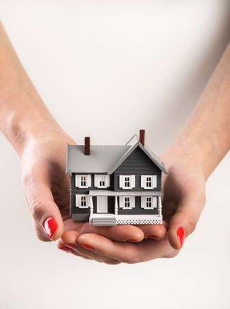 Woman holds a home building in her handsの写真素材
