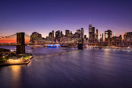 Brooklyn Bridge over the East River and the Manhattan downtown city skyline at night in New York USAの写真素材